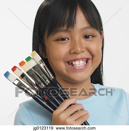 Asian girl holding paintbrushes with different colors on bristles View Large Photo Image Stock Photo - Asian girl holding paintbrushes with different colors on bristles. Fotosearch