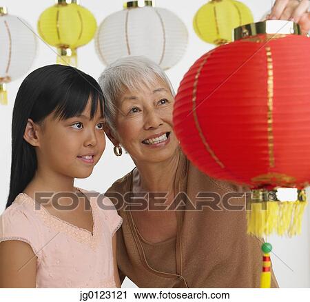 Stock Image - Asian grandmother and granddaughter looking at paper lanterns. Fotosearch