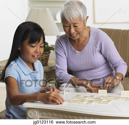 Stock Photograph - Asian grandmother and granddaughter playing dominoes. Fotosearch