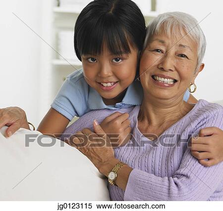 Asian grandmother and granddaughter hugging and on sofa View Large Photo Image Stock Photography - Asian grandmother and granddaughter hugging and on sofa. Fotosearch