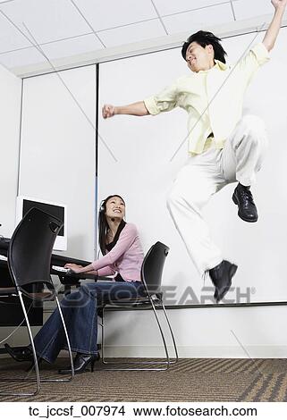 Asian man jumping next to Asian female computer service technician View Large Photo Image Picture - Asian man jumping next to Asian female computer service technician. Fotosearch