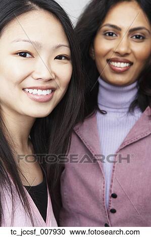 Stock Image - Asian woman and Indian woman smiling. Fotosearch