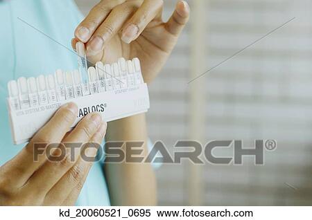 Stock Photography - Close up of dentist holding tooth color samples. Fotosearch