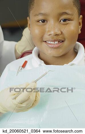 Close up of dentist's hand holding dental tool next to boy's mouth View Large Photo Image Picture - Close up of dentist's hand holding dental tool next to boy's mouth. Fotosearch