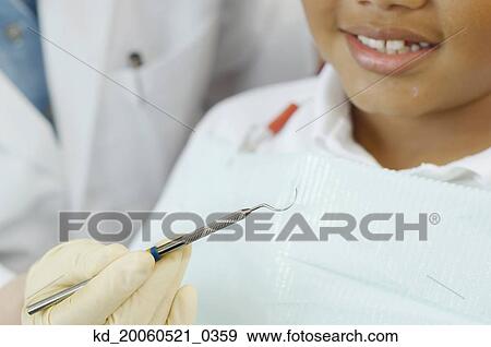 Close up of dentist's hand holding dental tool next to boy's mouth View Large Photo Image Stock Photo - Close up of dentist's hand holding dental tool next to boy's mouth. Fotosearch
