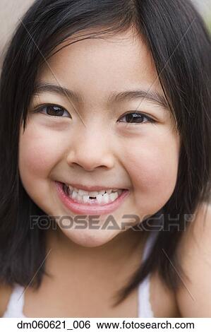 Close up of young Asian girl smiling with tooth missing View Large Photo Image Stock Photograph - Close up of young Asian girl smiling with tooth missing. Fotosearch