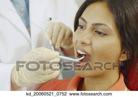 Dentist holding dental mirror in female patient's mouth View Large Photo Image Stock Image - Dentist holding dental mirror in female patient's mouth. Fotosearch