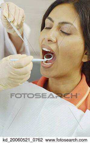 Dentist holding dental mirror in female patient's mouth View Large Photo Image Stock Image - Dentist holding dental mirror in female patient's mouth. Fotosearch