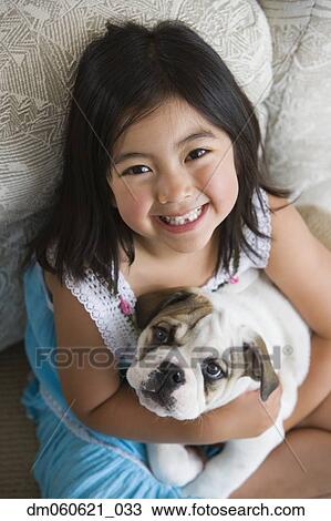 High angle view of young Asian girl holding puppy View Large Photo Image Stock Image - High angle view of young Asian girl holding puppy. Fotosearch