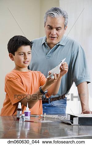 Picture - Hispanic father and son building model airplane. Fotosearch