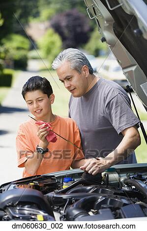 Stock Image - Hispanic father and son checking oil in car. Fotosearch