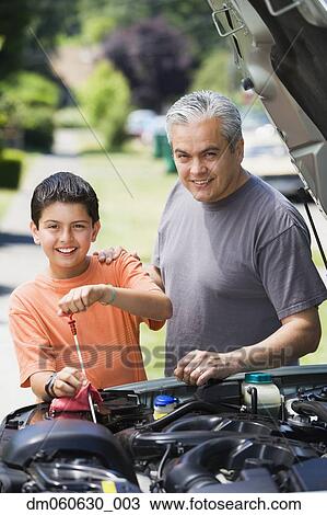 Stock Image - Hispanic father and son checking oil in car. Fotosearch