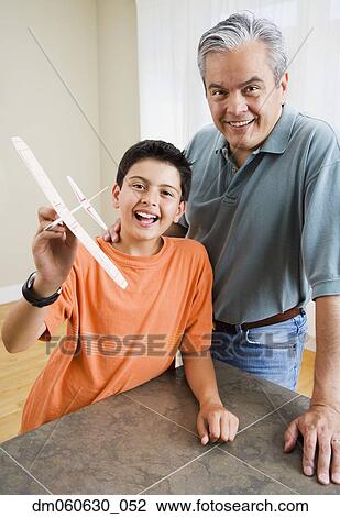 Stock Image - Hispanic father and son holding model airplane. Fotosearch