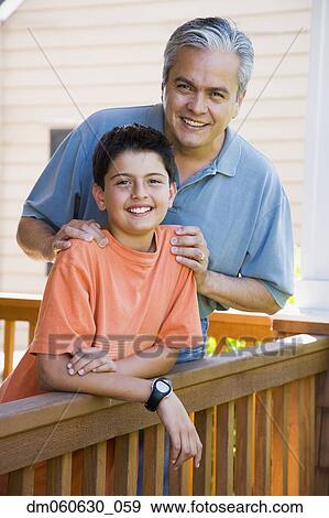 Stock Photo - Hispanic father and son smiling on porch. Fotosearch