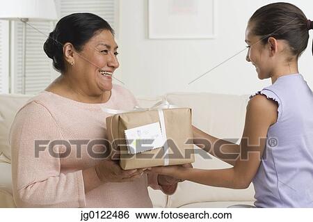 Hispanic girl giving gift to grandmother View Large Photo Image Stock Photograph - Hispanic girl giving gift to grandmother. Fotosearch