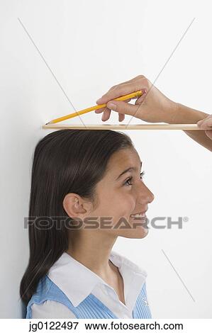 Stock Photo - Hispanic girl having height marked on wall. Fotosearch