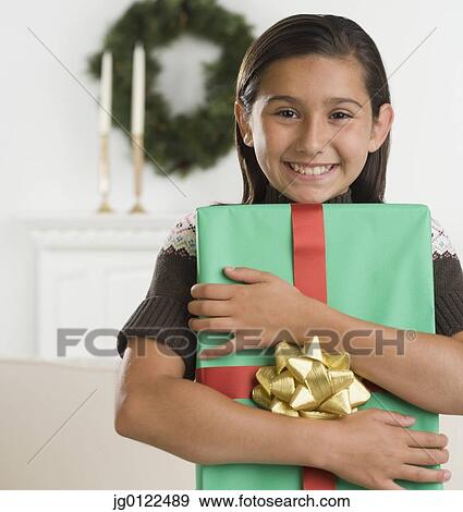 Hispanic girl holding gift and smiling View Large Photo Image Stock Photo - Hispanic girl holding gift and smiling. Fotosearch