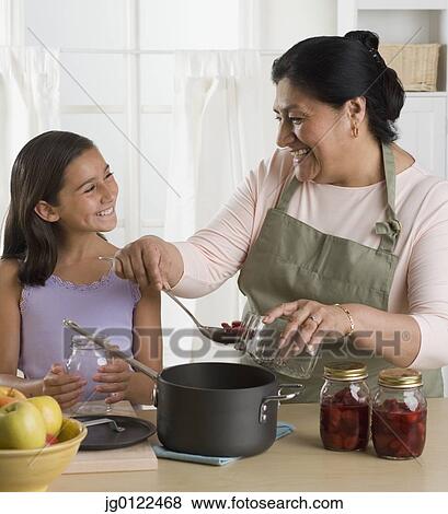 Stock Photo - Hispanic grandmother and granddaughter preparing food in kitchen. Fotosearch
