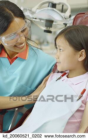 Indian female dental assistant smiling at young Asian female patient View Large Photo Image Stock Image - Indian female dental assistant smiling at young Asian female patient. Fotosearch