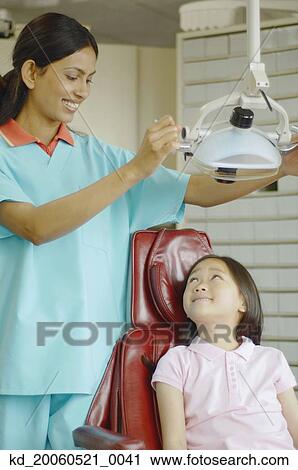 Indian female dental assistant with Asian girl in dentist's chair View Large Photo Image Stock Image - Indian female dental assistant with Asian girl in dentist's chair. Fotosearch