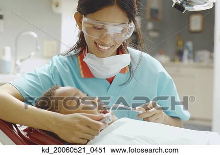 Indian female dental assistant working on African boy View Large Photo Image Stock Image - Indian female dental assistant working on African boy. Fotosearch