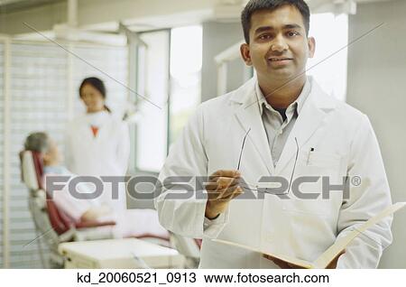 Indian male dentist with patient in background View Large Photo Image Stock Image - Indian male dentist with patient in background. Fotosearch