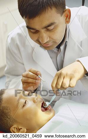 Indian male dentist working on African boy View Large Photo Image Stock Photo - Indian male dentist working on African boy. Fotosearch