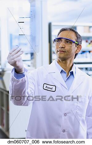 Stock Photograph - Indian male scientist looking at DNA film. Fotosearch