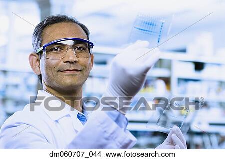 Indian male scientist smiling and holding DNA film View Large Photo Image Picture - Indian male scientist smiling and holding DNA film. Fotosearch