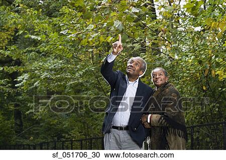 Stock Image - Senior African couple pointing in woods. Fotosearch