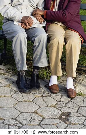 Stock Image - Senior African couple sitting on bench outdoors. Fotosearch