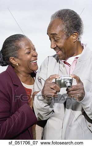 Stock Photo - Senior African couple with digital camera smiling at each other. Fotosearch
