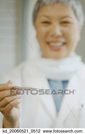 Senior Asian female dentist holding up dental tool View Large Photo Image Stock Image - Senior Asian female dentist holding up dental tool. Fotosearch