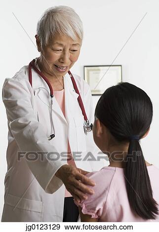 Senior Asian female doctor talking to young patient View Large Photo Image Stock Photo - Senior Asian female doctor talking to young patient. Fotosearch
