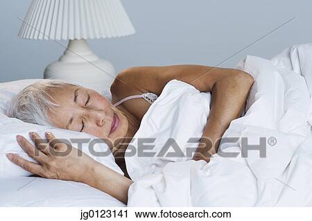 Stock Image - Senior Asian woman sleeping in bed. Fotosearch