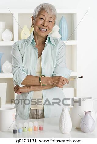 Senior Asian woman smiling with pottery and paints View Large Photo Image Stock Image - Senior Asian woman smiling with pottery and paints. Fotosearch