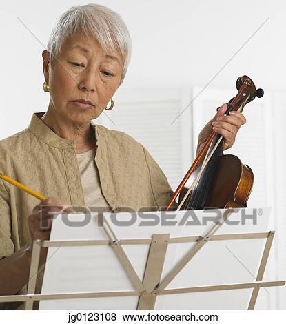 Stock Photo - Senior Asian woman with violin and sheet music. Fotosearch
