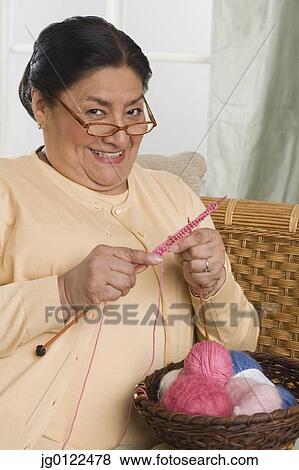 Stock Photo - Senior Hispanic woman knitting and smiling. Fotosearch