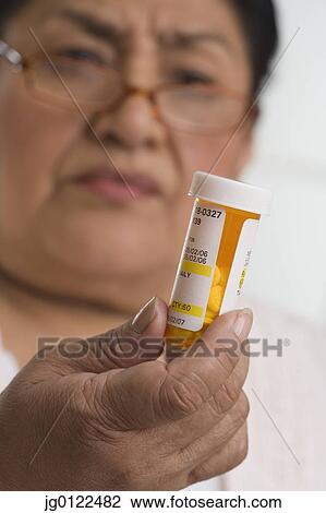 Senior Hispanic woman looking at medication bottle View Large Photo Image Stock Image - Senior Hispanic woman looking at medication bottle. Fotosearch