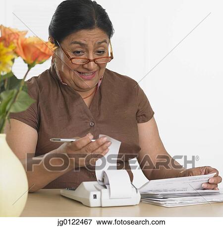 Senior Hispanic woman paying bills View Large Photo Image Stock Photo - Senior Hispanic woman paying bills. Fotosearch