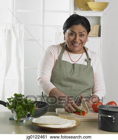 Stock Image - Senior Hispanic woman preparing food in kitchen. Fotosearch