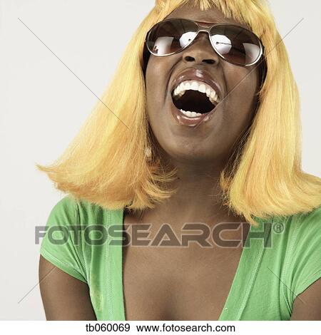 Stock Photo - Studio shot of African woman wearing blonde wig and sunglasses. Fotosearch
