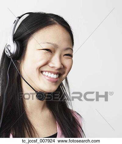 Picture - Studio shot of young Asian woman with headset smiling. Fotosearch