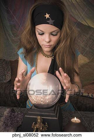 Stock Image - Woman dressed at fortune teller looking into crystal ball. Fotosearch