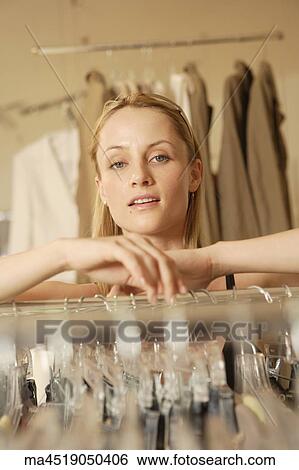 Stock Photograph - Woman leaning on rack at clothing store. Fotosearch