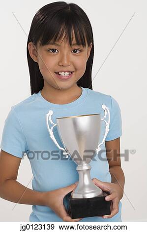 Young Asian girl holding trophy and smiling View Large Photo Image Stock Photo - Young Asian girl holding trophy and smiling. Fotosearch