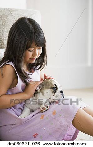 Young Asian girl petting puppy in lap View Large Photo Image Stock Photograph - Young Asian girl petting puppy in lap. Fotosearch