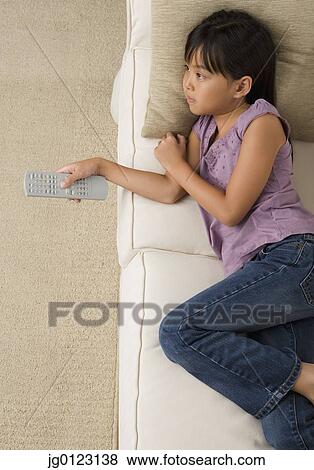 Young Asian girl watching television on sofa View Large Photo Image Stock Photo - Young Asian girl watching television on sofa. Fotosearch