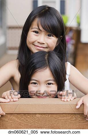 Stock Photography - Young Asian sisters hugging and smiling indoors. Fotosearch