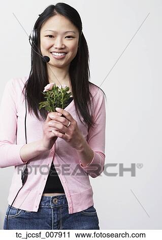 Young Asian woman with headset holding flowers View Large Photo Image Stock Image - Young Asian woman with headset holding flowers . Fotosearch